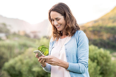 BIE a Hero: Sammle Bäume mit umweltfreundlichem Handeln! BIE a Hero: Sammle Bäume mit umweltfreundlichem Handeln! | Frau mit Handy in der Hand. Aus dem Handy wachsen Bäume.