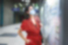 Frau mit Maske steht in einer unterirdischen StadtBahn-Haltestelle vor einer Informationsvitrine..