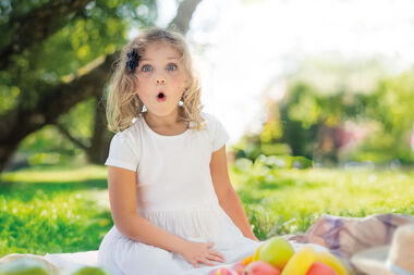 Mädchen sitzt auf einer Picknickdecke und macht ein überraschtes Gesicht. | Picknick trifft Theater: 4. bis 6. Juli 2025 im Senner Waldbad