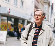 Ein älterer Mann schlendert fröhlich durch die Stadt.