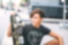 Ein junger Teenager sitzt mit Skateboard an einer Rampe.