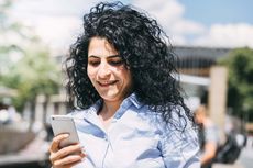 Eine Frau schaut an der StadtBahn-Haltestelle auf ihr Handy.