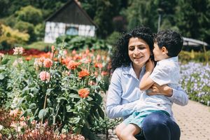 Ein Kind flüstert seiner Mutter im Park etwas ins Ohr.