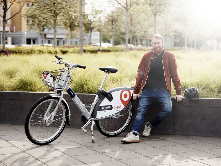 Ein Mann sitzt lächelnd neben einem Siggi-Fahrrad am Kesselbrink