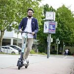 Mann fährt auf einem TIER E-Tretroller auf dem Radweg
