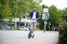 Mann fährt auf einem TIER E-Tretroller auf dem Radweg