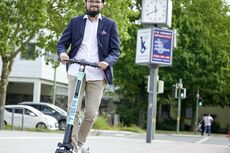 Mann fährt auf einem TIER E-Tretroller auf dem Radweg