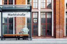 Dame mit Rollator sitzt an der Haltestelle Marktstraße.