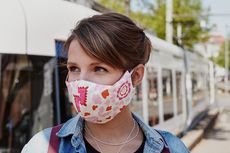 Frau mit Mund-Nasen-Schutz vor einer StadtBahn.