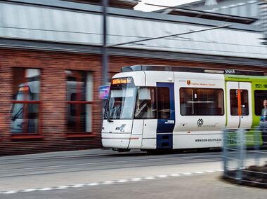 Vamos-Bahn fährt an Haltestelle ein.