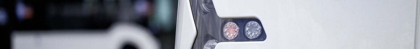 Scheinwerfer und Blinker der Vamos-StadtBahn in der Nahaufnahme, im Hintergrund ein moBiel-Bus.