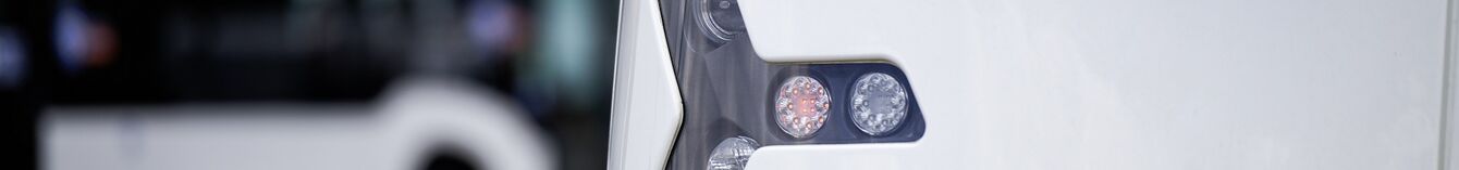 Scheinwerfer und Blinker der Vamos-StadtBahn in der Nahaufnahme, im Hintergrund ein moBiel-Bus.