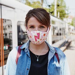 Frau mit Mund-Nasen-Schutz vor einer StadtBahn.