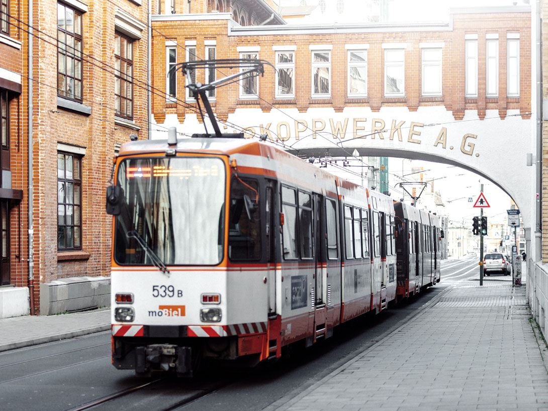 Bahn fährt unter dem Bogen der Dürkoppwerke entlang.